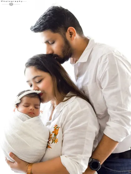 A variation of the family kiss, this image captures the mother kissing her baby's head while the father kisses hers. A beautiful cascade of affection.