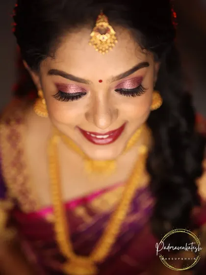 A top-down view showcasing the detailed eye makeup for a South Indian bride. The shimmering rose-gold eyeshadow and dramatic lashes are paired with a deep red lip, creating a timeless and photogenic bridal look.