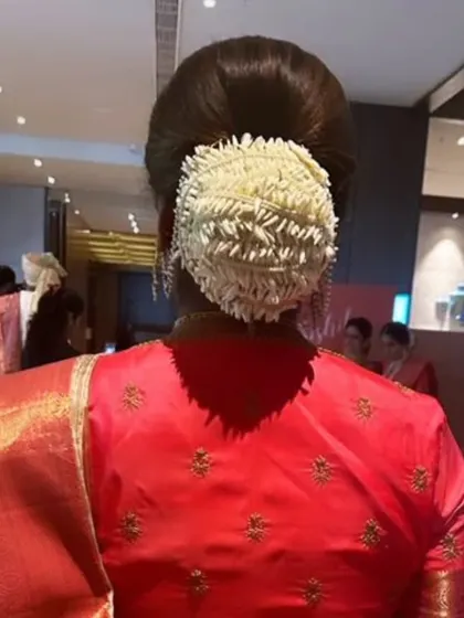 A full, round bun completely covered in a woven gajra of fresh jasmine, a classic look for silk sarees.