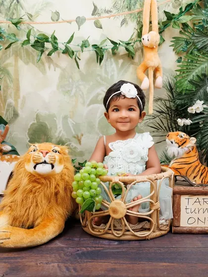 A personalized jungle-themed first birthday for Tara, complete with animal props and a custom sign.