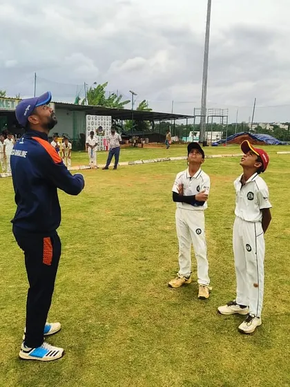 A coach demonstrates the technique for taking high catches to two young, attentive players.