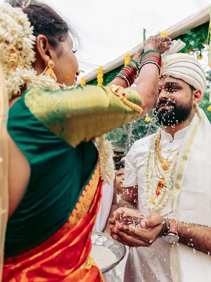 The bride and groom performing the 'talambralu' ritual, where they shower each other with rice and turmeric. We ensure the setup allows for these fun and photogenic traditions.