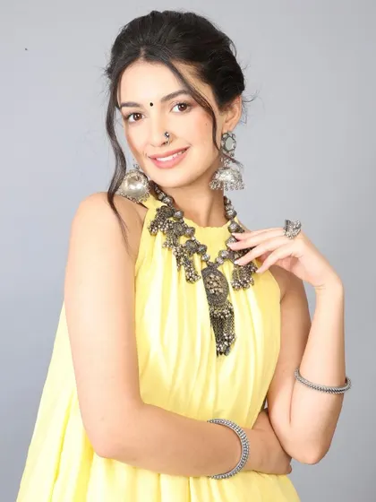 A smiling portrait from the yellow dress shoot, showing how the makeup appears fresh and natural. The look features a classic bindi and nose ring, styled for a traditional yet modern appeal.