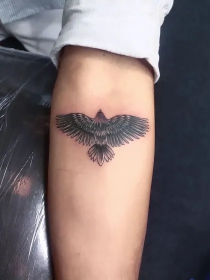 After: The finished eagle tattoo, with its detailed wings and solid black shading, completely hides the old date. This is a great example of using a powerful animal design for a cover-up.