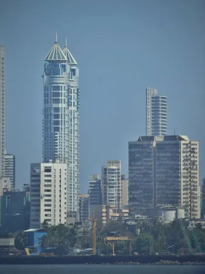 A telephoto shot of the Mumbai Twin Towers from across the water at Marine Drive, highlighting the city's modern skyline.