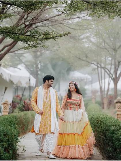 A romantic walk through a misty garden. The couple's colorful outfits for their Haldi ceremony stand out beautifully against the soft, dreamy background.