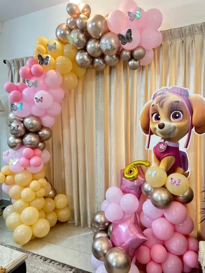 A Paw Patrol theme focused on the character Skye, with a pink, yellow, and chrome gold balloon arch.