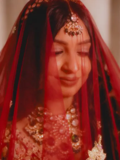 A soft, dreamy portrait of the bride, Priyanka, through her red veil. This shot is full of romance and mystique.