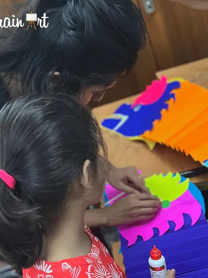 An instructor helps a student assemble her vibrant paper dragon. These projects are a great way to learn about culture while practicing crafting skills like folding and gluing.