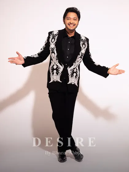An expressive, full-length view of the black blazer with white baroque embroidery. This piece is designed to offer both commanding presence and freedom of movement.