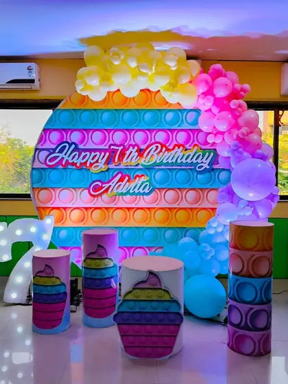 We stay on top of the latest trends, like this vibrant 'Pop It' theme for a 7th birthday. The setup includes a custom printed backdrop, themed props, a light-up number '7', and a colorful balloon cascade.