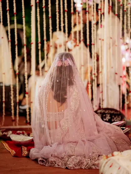 A poignant shot from behind of a bride during her Nikah ceremony, her veil softly covering her as she prays.