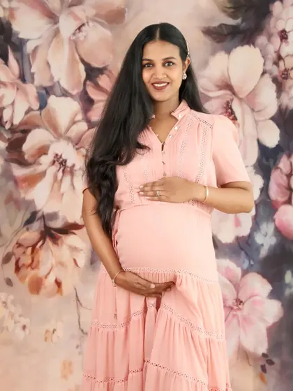 A beautiful and classic portrait of a mom-to-be in a pink dress. The floral background adds a touch of romance and softness to the image.