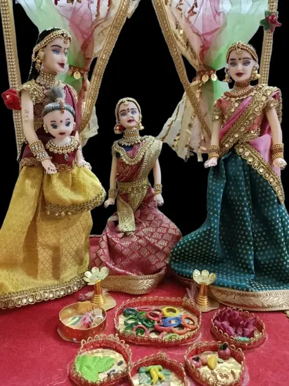 A close-up of the seemantham doll set, highlighting the small baby doll being held by one of the figures.