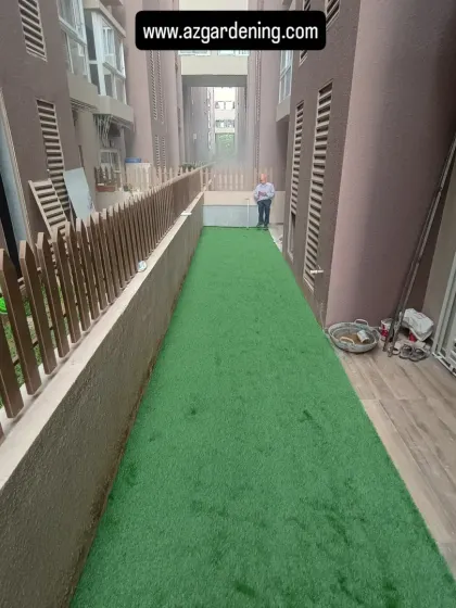 The finished result of the side yard conversion. The new artificial lawn is clean, level, and bordered by a small fence, making the space both attractive and functional.