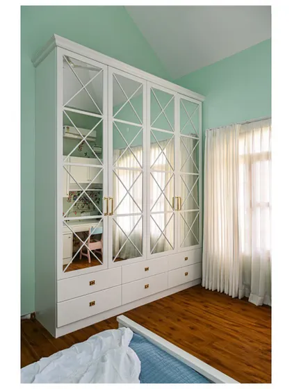 A daughter's room in a mint and white combination, with a large mirrored wardrobe that makes the space feel larger and brighter.
