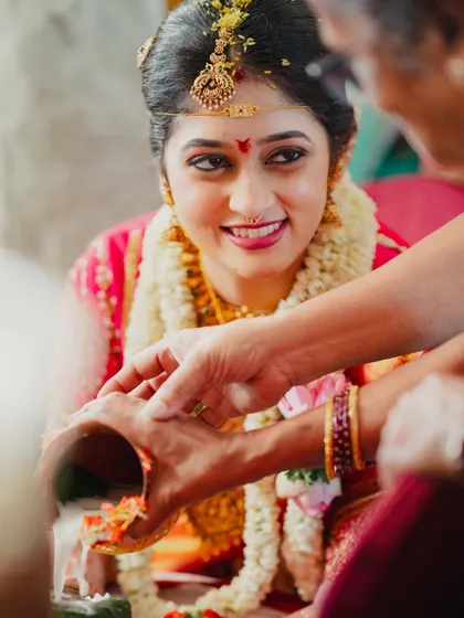 A close-up of the bride during a wedding ritual. Her makeup is soft and natural, allowing her happy expressions to be the main focus.