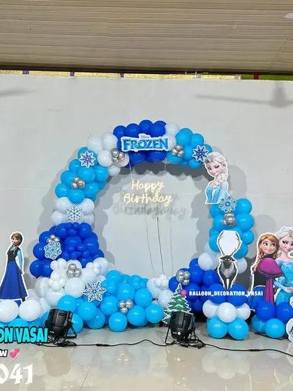 A large-scale Frozen theme for a first birthday. This hall decoration includes a balloon arch, a custom backdrop, and cutouts of all the main characters from the movie.