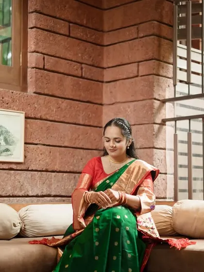 A serene portrait of the bride in a moment of quiet contemplation, highlighting the intricate details of her saree and the warm, earthy tones of the room.
