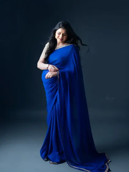 A simple and elegant solo portrait. The movement in her hair and the graceful drape of the blue saree create a dynamic and beautiful image.