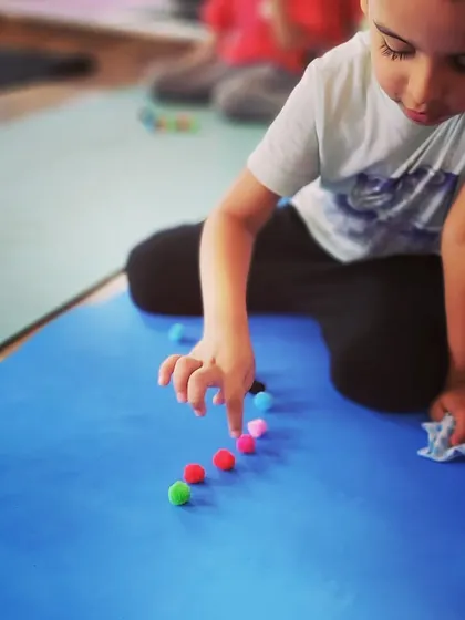 A fine motor skill activity using pompoms during a kids' class. We incorporate activities that enhance concentration alongside physical poses.