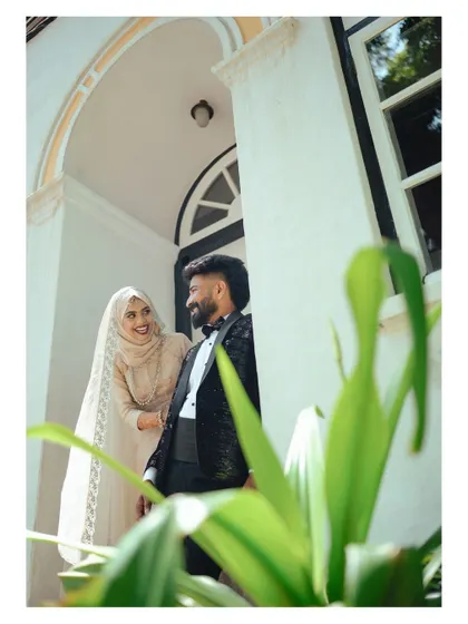 A beautifully framed shot of the couple on a balcony, with lush greenery adding a natural element to the portrait.