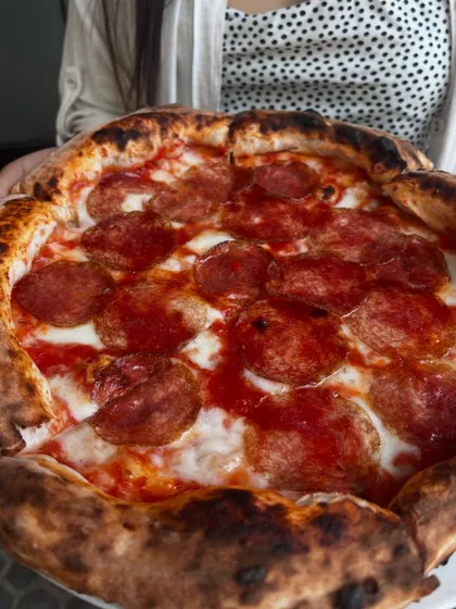 Holding up a freshly baked Hungarian Salami pizza. It's a feast for the eyes and the stomach.