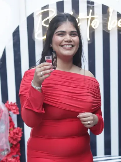 The bride-to-be, radiant in red, raising a toast to her upcoming wedding.