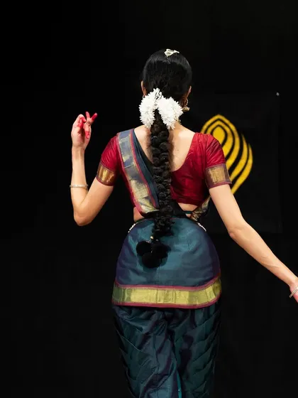 A simple yet elegant pose from behind, highlighting the traditional braided hairstyle adorned with flowers (gajra), an essential part of the dancer's look.