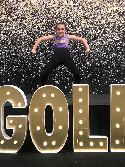 A fun, strong pose from an Xcel Gold gymnast celebrating the end of a successful season.