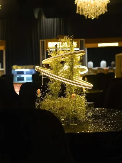 A close-up of the unique, modern centerpiece. A spiral of neon light is intertwined with baby's breath, creating a futuristic and artistic floral arrangement.
