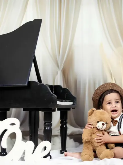 A tender moment as the little boy hugs a teddy bear during his piano-themed shoot.