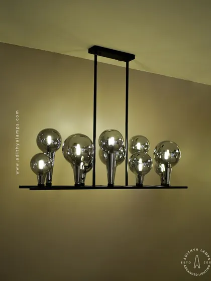 A playful yet chic linear chandelier featuring a series of chrome-finished glass bubbles. The highly reflective surface and modern design make it a striking addition to a kitchen island or a contemporary dining space.