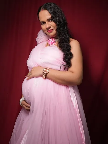 A studio shot of a client in the pink maternity gown. The simple red backdrop makes the colour of the dress pop.