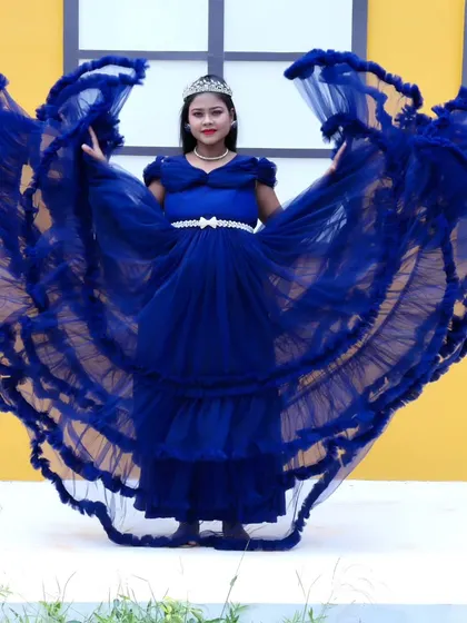 A dramatic shot of a royal blue ruffled maternity gown, with the trail fanned out like wings.