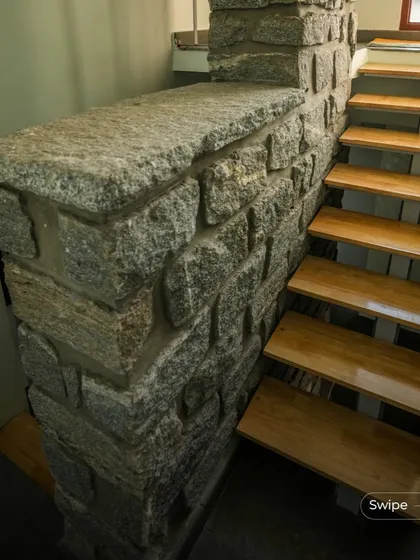 A detail of the stone masonry supporting the wooden steps of the staircase, highlighting the beautiful contrast between the two natural materials.