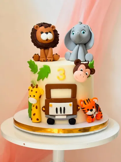 A safari jeep adventure cake for a third birthday. This design includes a giraffe, tiger, monkey, elephant, and lion ready for a ride.