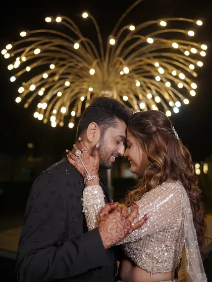 A romantic close-up of the couple. The bride's sangeet look features soft curls, a delicate haathphool, and shimmery makeup that catches the light perfectly.