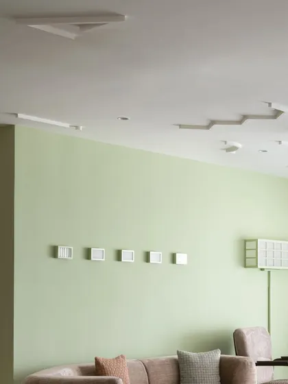 A detail of the living room, where a snug duo of armchairs is set against a green-apple-hued wall, creating a perfect spot for conversation.