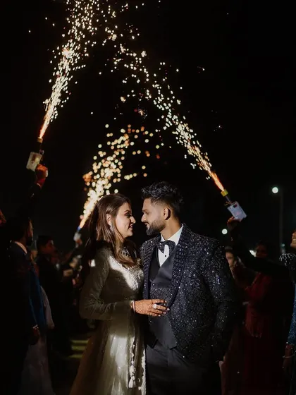 A grand entrance for the couple, surrounded by friends holding cold pyro sparklers. This creates a tunnel of light and celebration, making for an unforgettable start to their sangeet night.