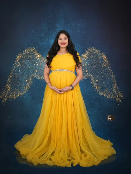 Golden hour glow. This mom-to-be looks like a celestial being in her yellow gown, complete with sparkling golden angel wings against a deep blue backdrop.