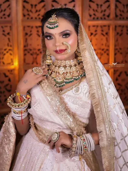 A confident portrait of the bride in her white and gold lehenga. The intricate details of the outfit are clearly visible, and her pose exudes grace and poise.