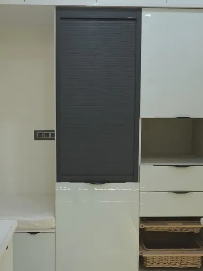 Smart storage is key in this kitchen, with a tall unit featuring a rolling shutter to neatly conceal appliances, and wicker baskets for vegetable storage.