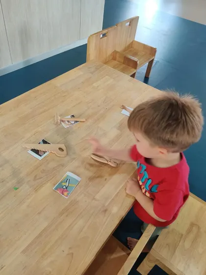 This boy points to a card, successfully matching it with a wooden tool. These small successes build confidence and a love for learning.