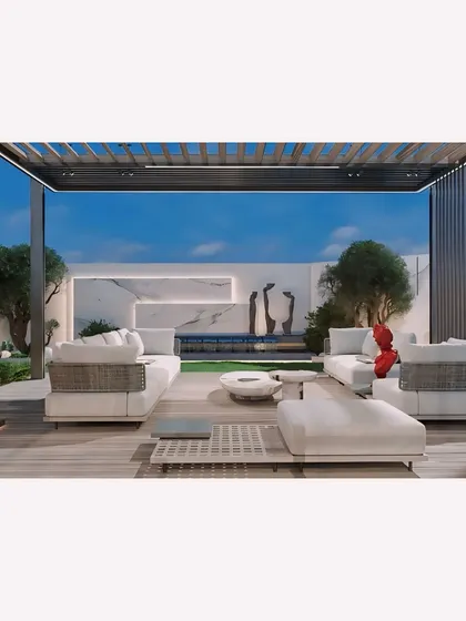 A modern landscape for the Jain residence in Panchsheel Enclave. This view shows the main lounge area on a wooden deck under a pergola, looking out towards a serene water feature and manicured lawn.