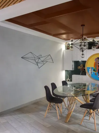 The dining area in the Grey Apartment is designed to spark conversation. A feature wall with recessed niches proudly displays the client's handpicked artifacts, while a custom chandelier adds drama and elegance.