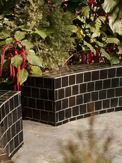 The landscape design for Pavilion House includes these curved benches made of black tiles, which snake through the garden.