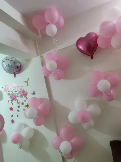 Simple pink and white balloon flowers on the wall as part of a 'Welcome Baby' home decoration.