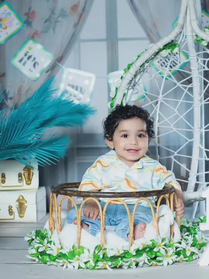 A beautiful half-birthday setup with a teal and white color scheme, complete with a cake and a hanging chair.