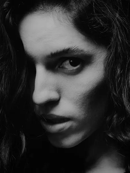 A raw, intense black and white portrait. The hard side light, known as Rembrandt lighting, creates a dramatic triangle of light on the cheek and carves out the model's features.